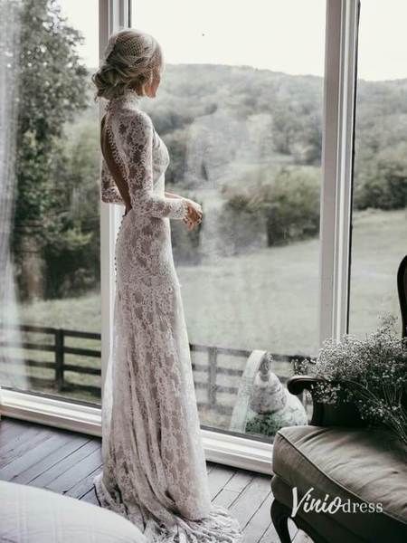 a woman standing in front of a window wearing a white lace dress with long sleeves