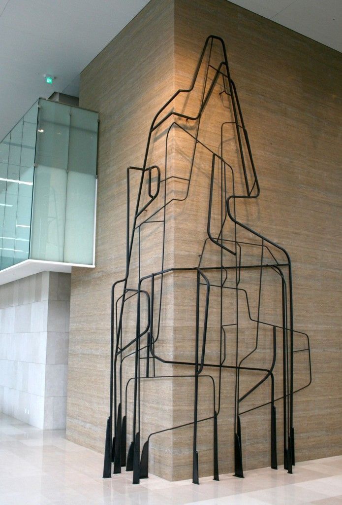 a large metal sculpture sitting in the middle of a room next to a stair case