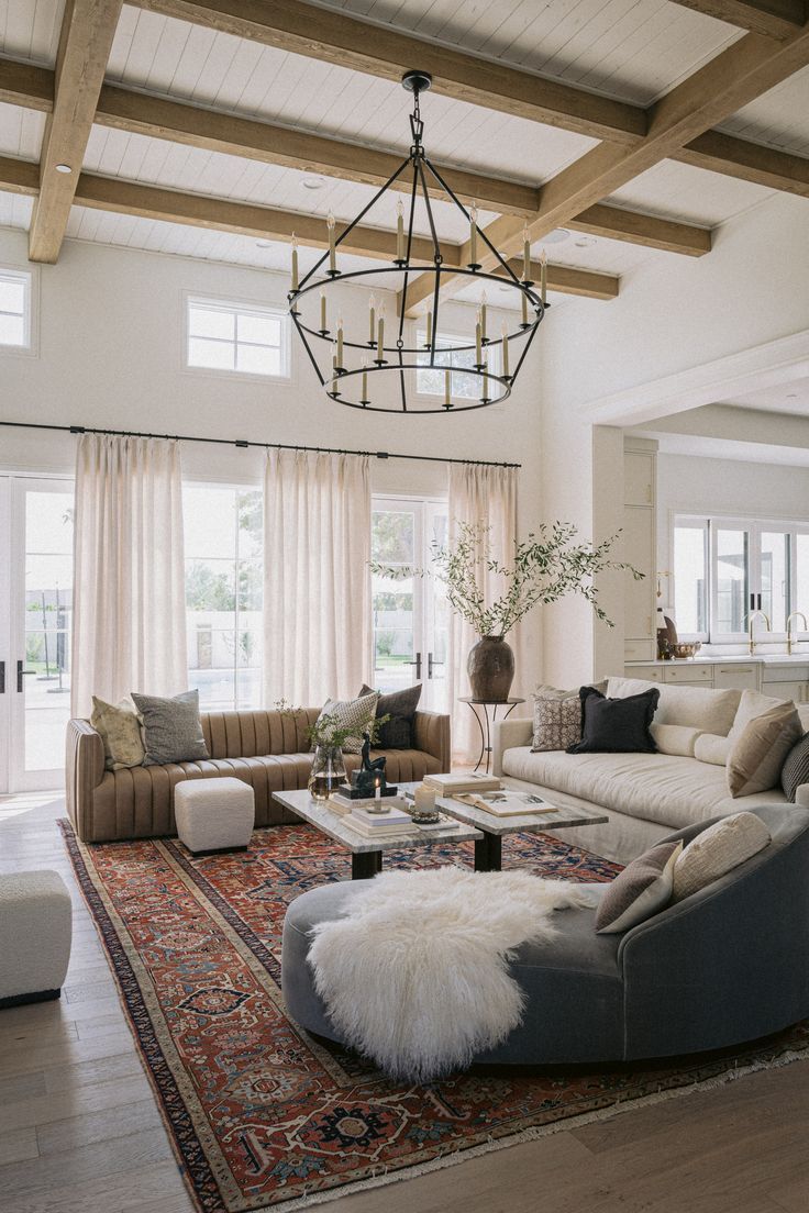 a living room filled with lots of furniture and a chandelier hanging from the ceiling