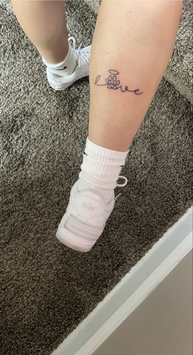 a woman's legs with the word love tattooed on her left leg and white tennis shoes