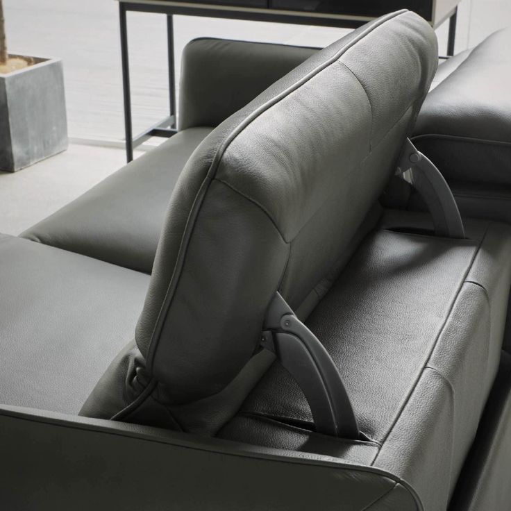 the back end of a gray couch with black leather upholster and arm rest