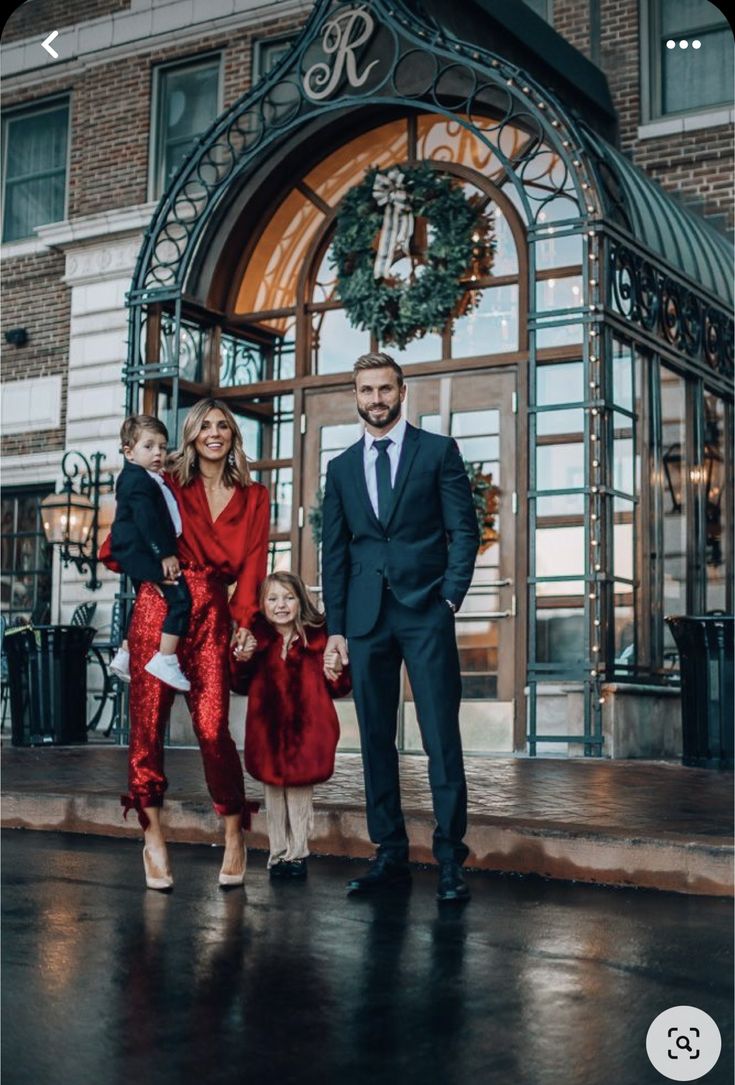 a man and two children standing in front of a building with a christmas wreath on it