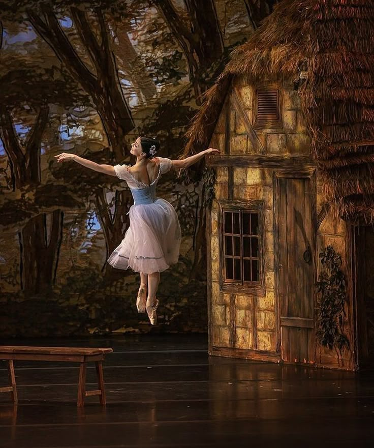 a ballerina is jumping in the air near a small house and tree lined area