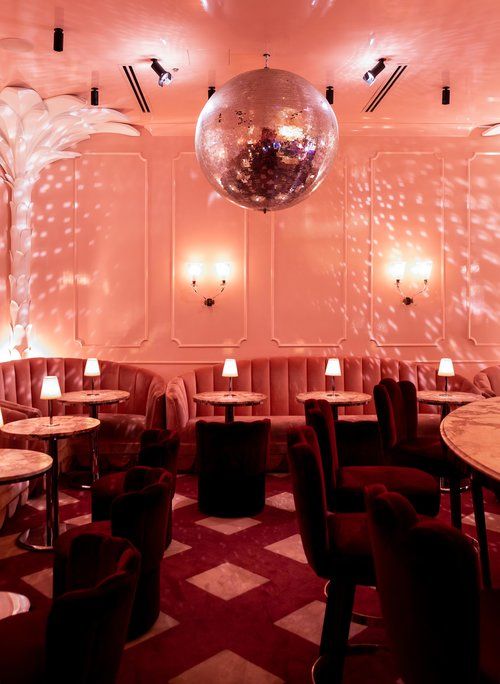 a room filled with lots of tables and chairs next to a disco ball hanging from the ceiling