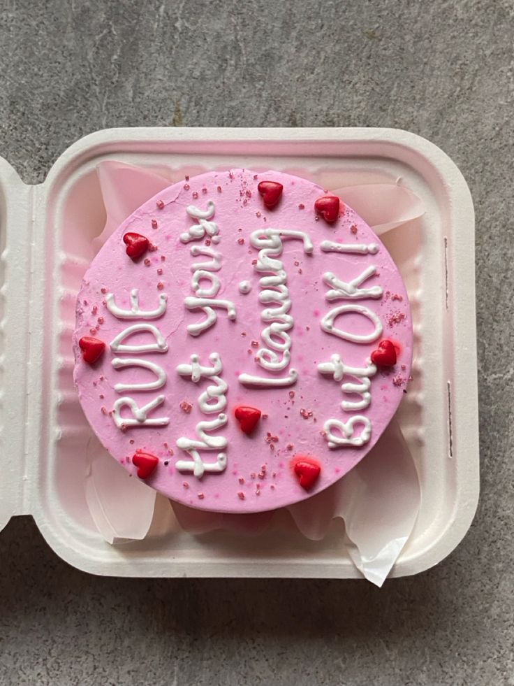 a pink cake in a plastic container with writing on it