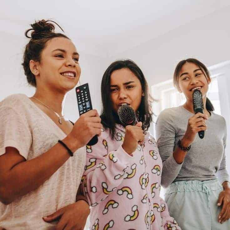 three women standing in a room holding microphones and talking to each other while one woman holds a remote control