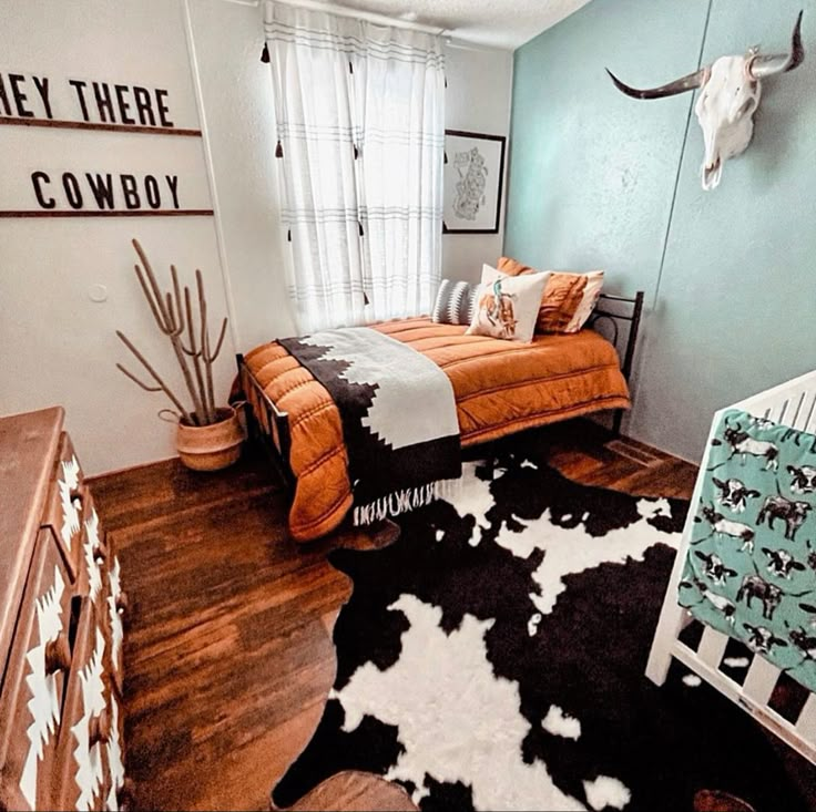 a bedroom with a cow print rug and wooden flooring, along with an animal head mounted on the wall