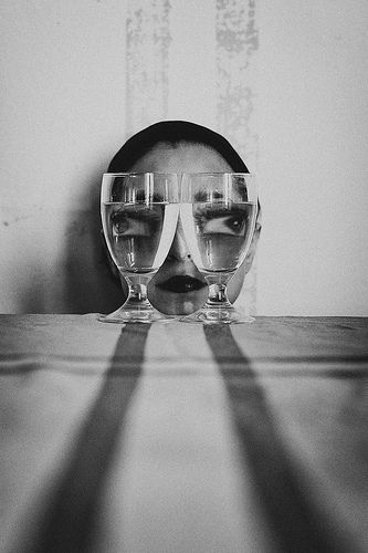 a woman's face behind two wine glasses