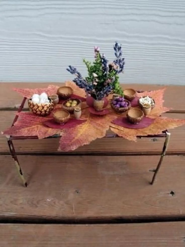 a table topped with leaves and flowers on top of a wooden floor