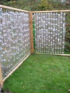 an outdoor area with green grass and plastic bottles in the fenced off area,