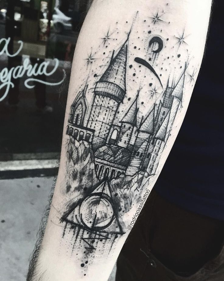 a black and white photo of a hogwarts castle tattoo on the right arm