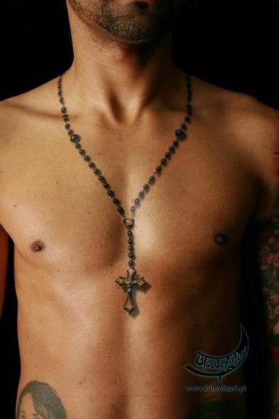 a shirtless man with tattoos on his chest wearing a rosary necklace and cross pendant