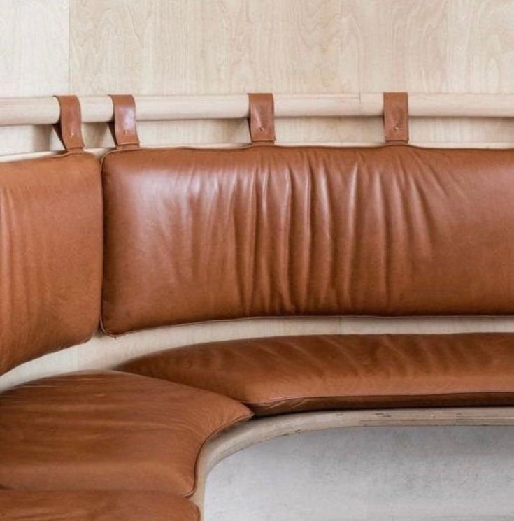 a brown leather couch sitting on top of a white floor next to a wooden headboard