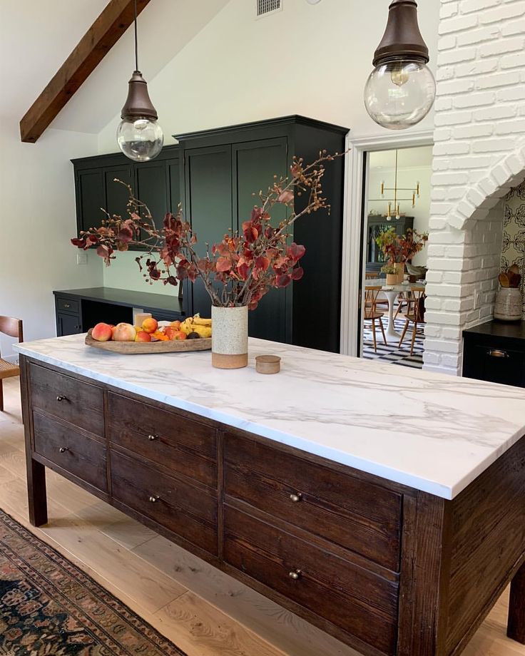 the kitchen island is made out of wood and has white marble counter tops, with two hanging lights above it