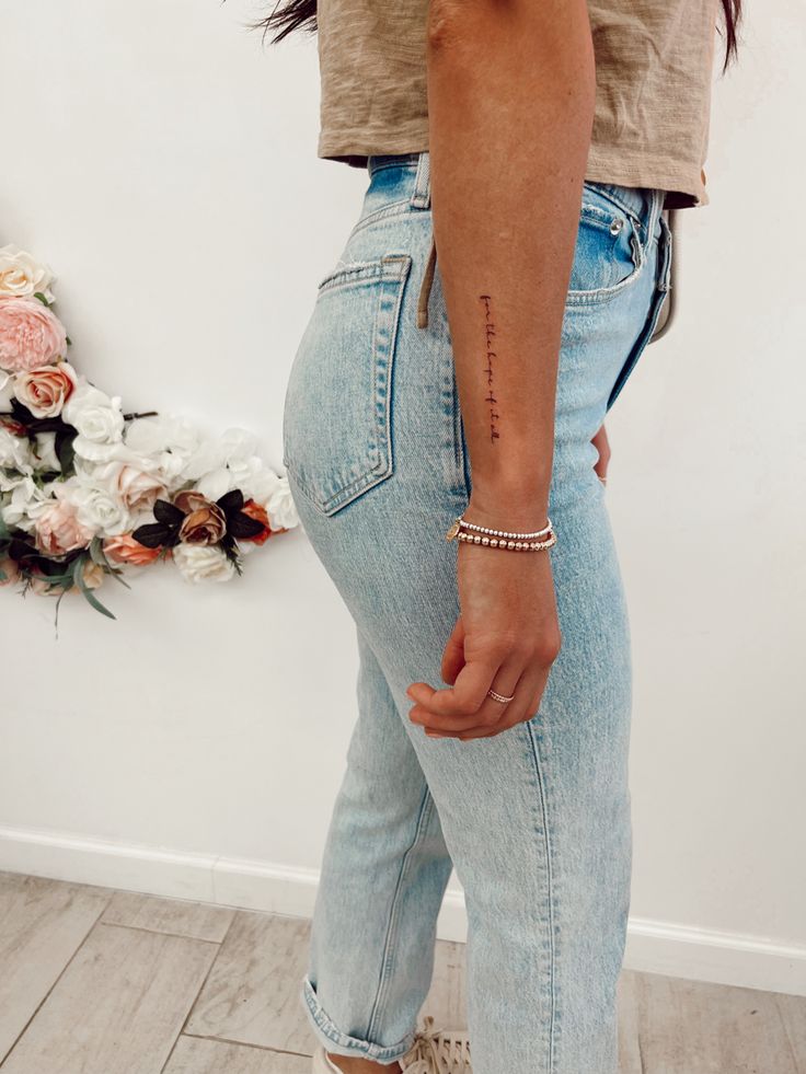 a woman with her hand in her pocket and the word love tattooed on her left arm