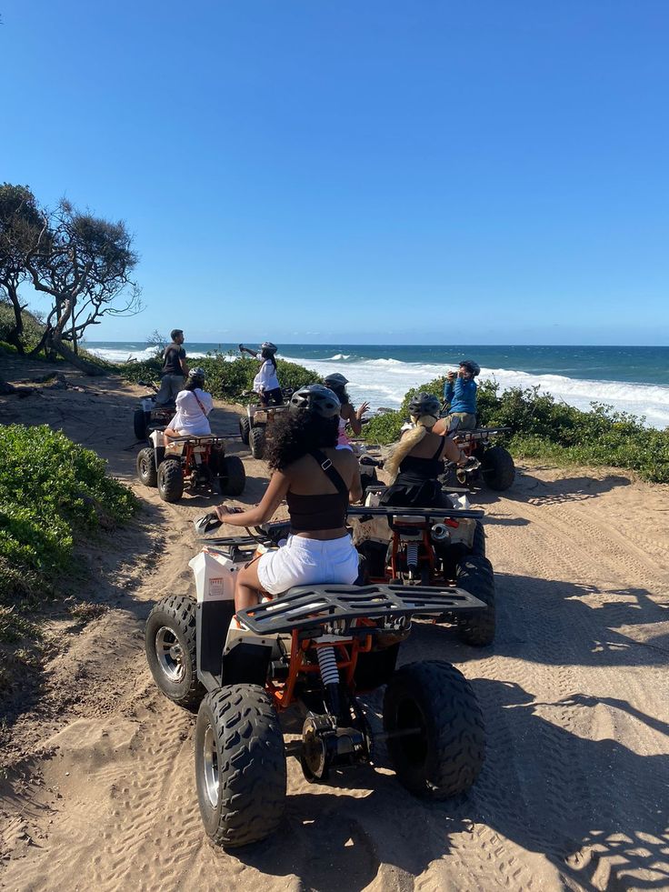 several people riding four wheelers on the beach