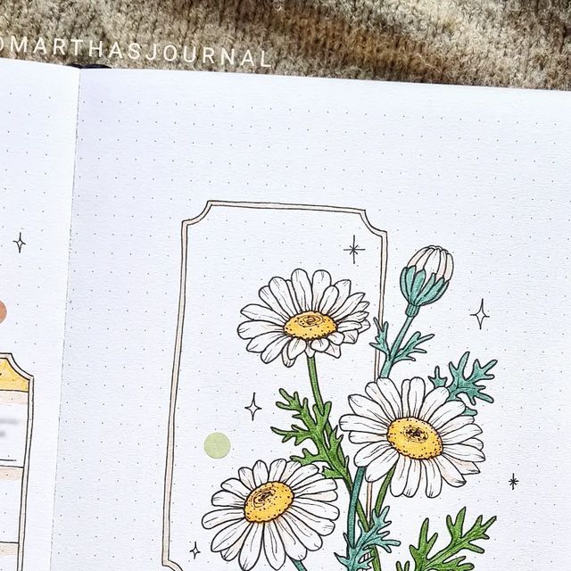 an open notebook with flowers on it and the inside pages are lined in dotted lines