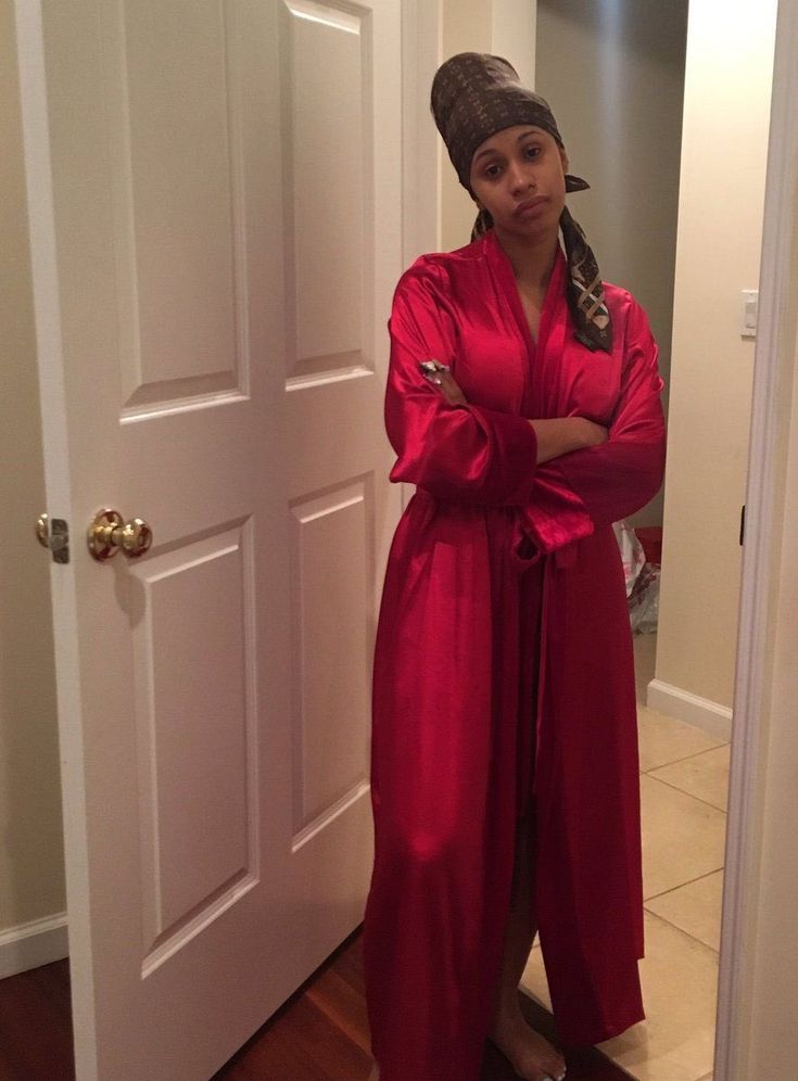 a woman standing in front of a door wearing a red robe