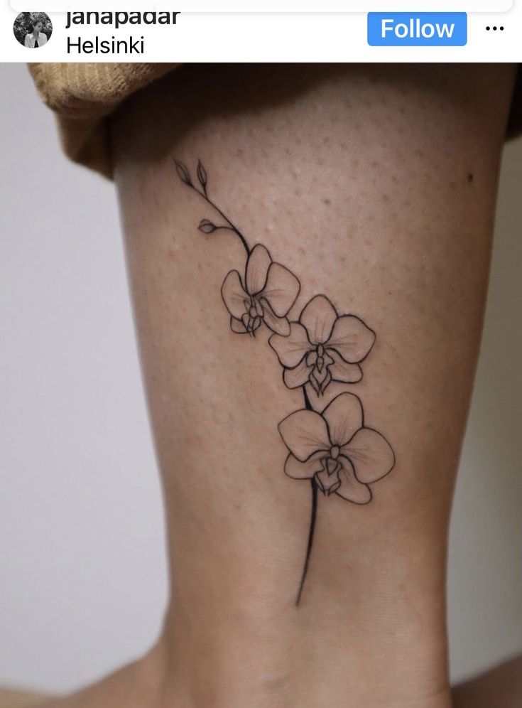 a small flower tattoo on the back of a woman's leg, with an inscription below it