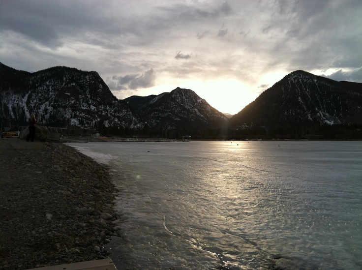 the sun is setting over mountains and water