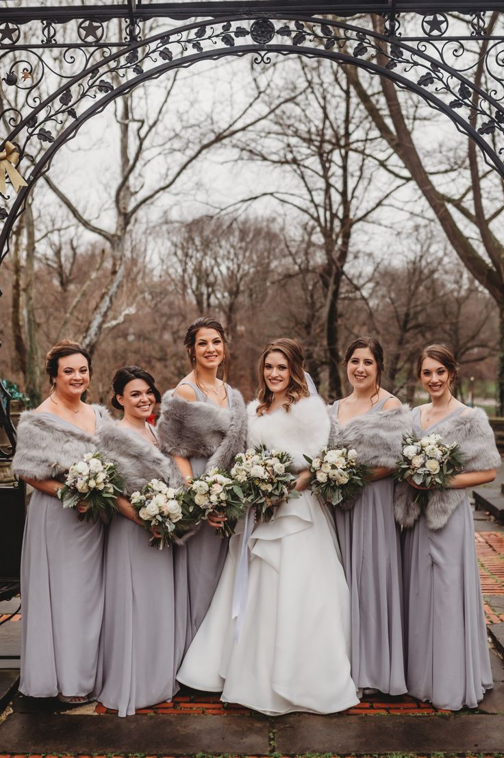 a group of women standing next to each other in front of a gazebo with flowers