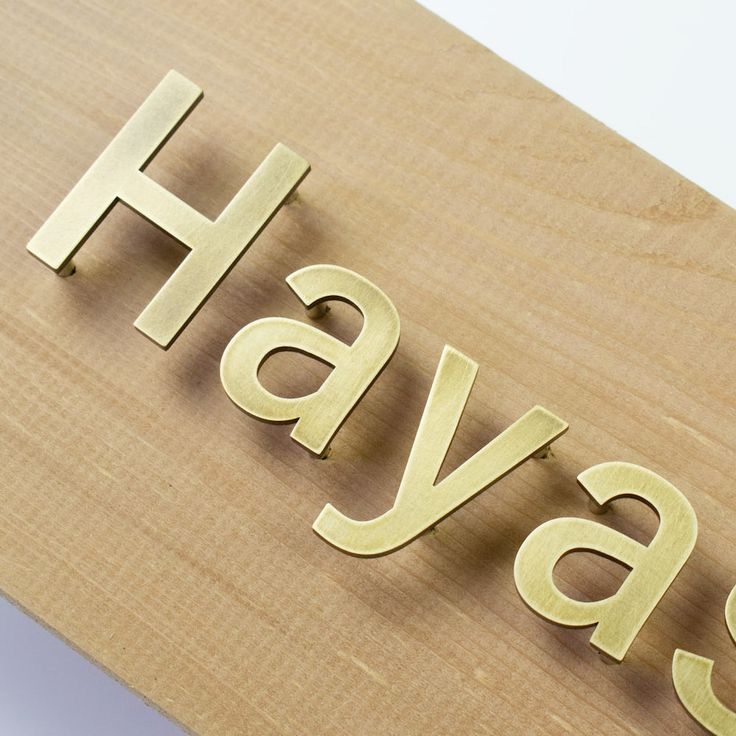 the word hay spelled with wooden letters on top of a piece of plywood board