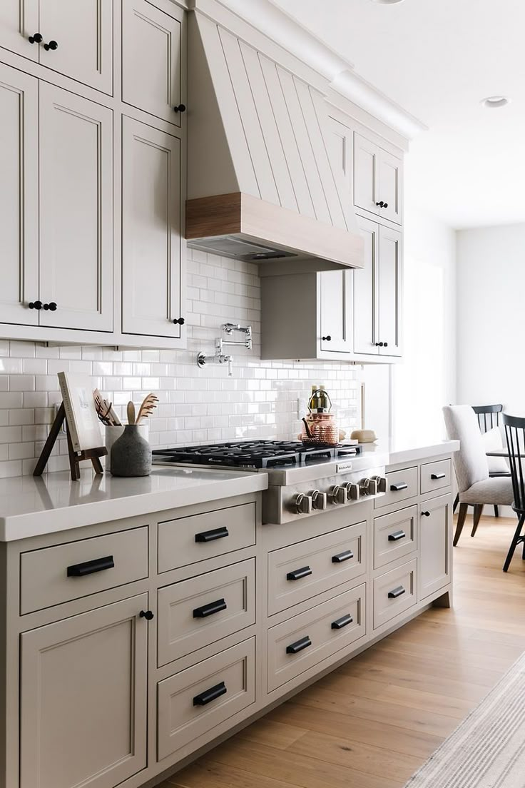 a kitchen with white cabinets and an island in the middle is seen from across the room