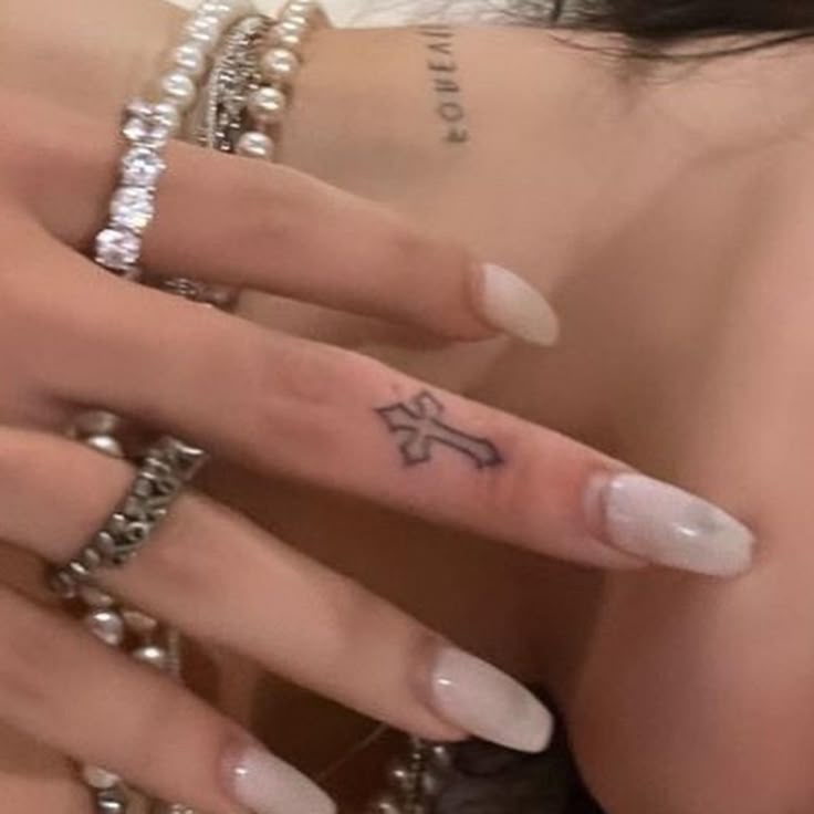 a woman's hand with a cross tattoo on it