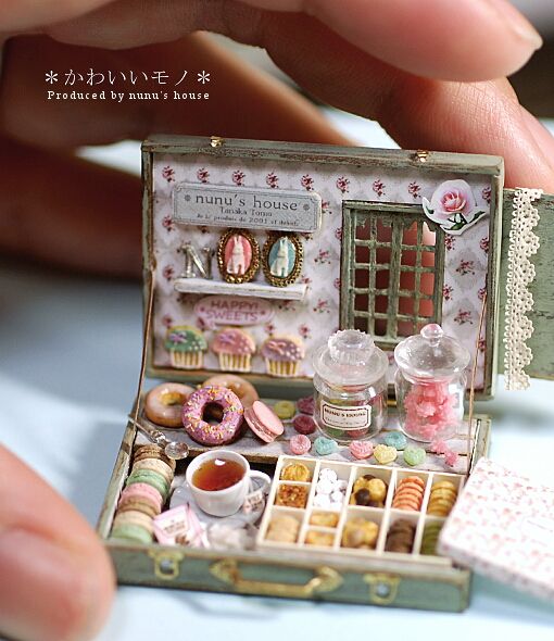 a miniature doll house with donuts, tea and cookies in it's box