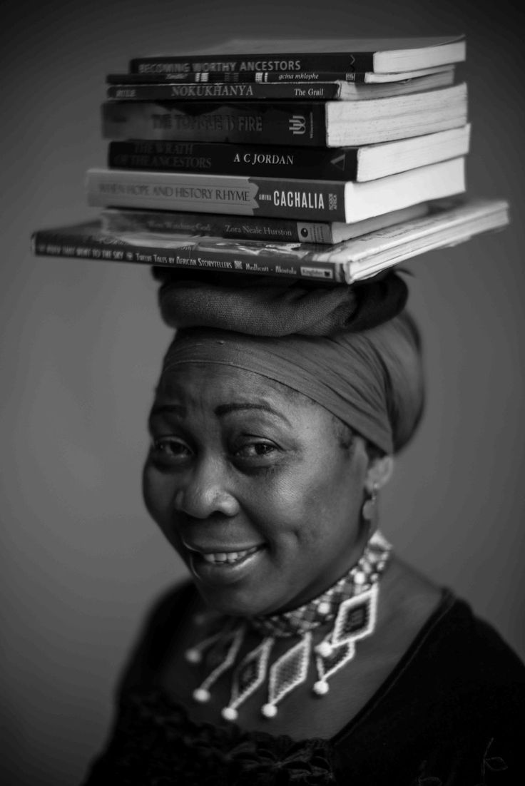 a woman wearing a stack of books on top of her head in black and white