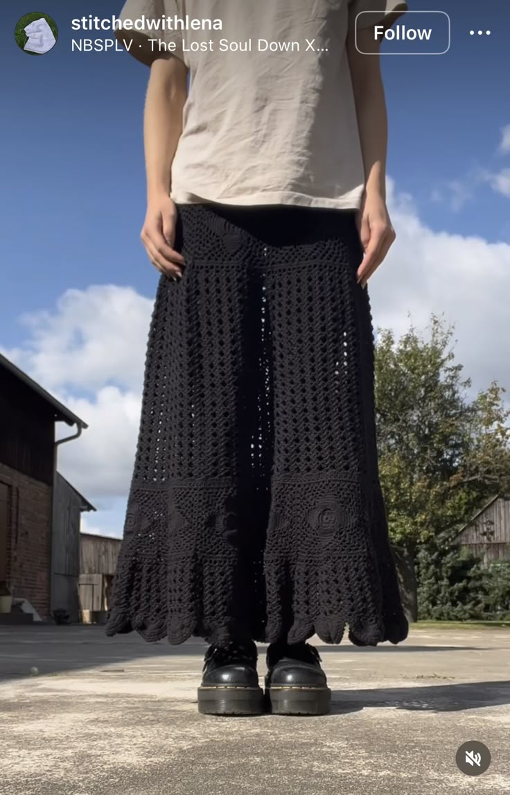 a person standing in front of a building wearing black crocheted pants and sneakers