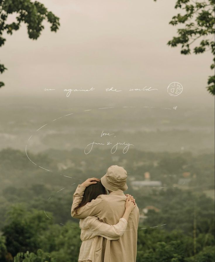 two people standing next to each other on top of a hill