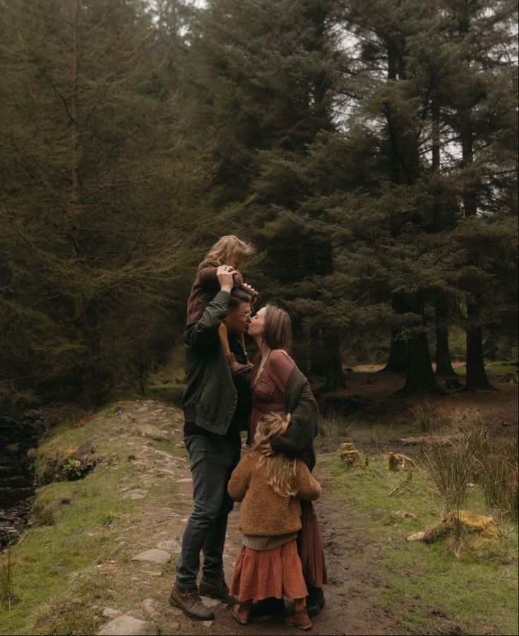 three people are standing on a path in the woods and one person is taking a photo