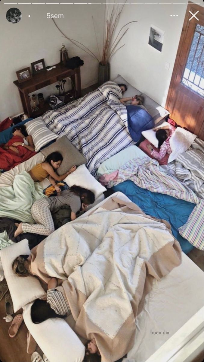 several people laying in bed with blankets and pillows on top of the bedspread