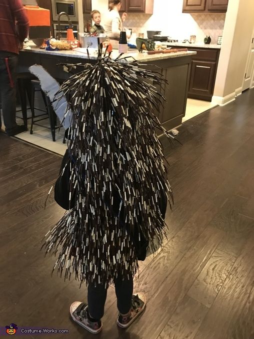 a young child dressed up as a bird on a skateboard in the middle of a kitchen