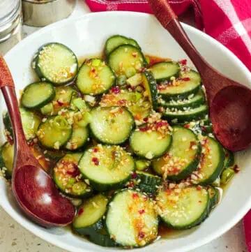 a white bowl filled with sliced cucumbers and sauce