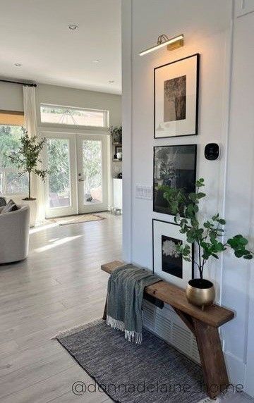 a living room with pictures on the wall and a bench in front of the door