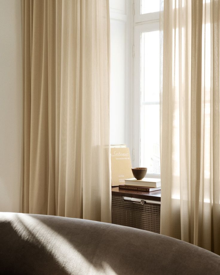 the sun shines through the curtains in this bedroom with a bed and nightstand next to it