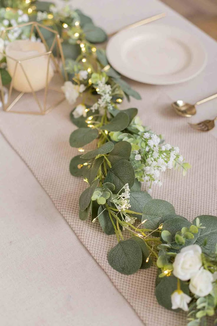 the table is set with white flowers and greenery