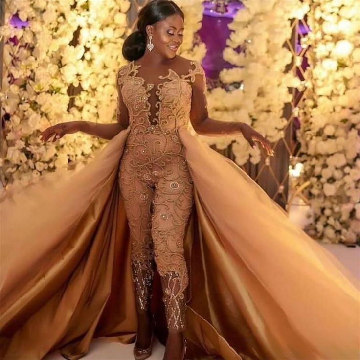 a woman in a gold gown standing next to flowers