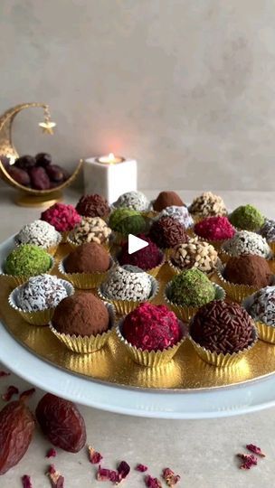 a platter filled with chocolates and nuts next to a lit candle on a table