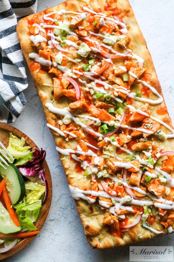 a pizza with dressing on it next to a bowl of salad and a plate of vegetables