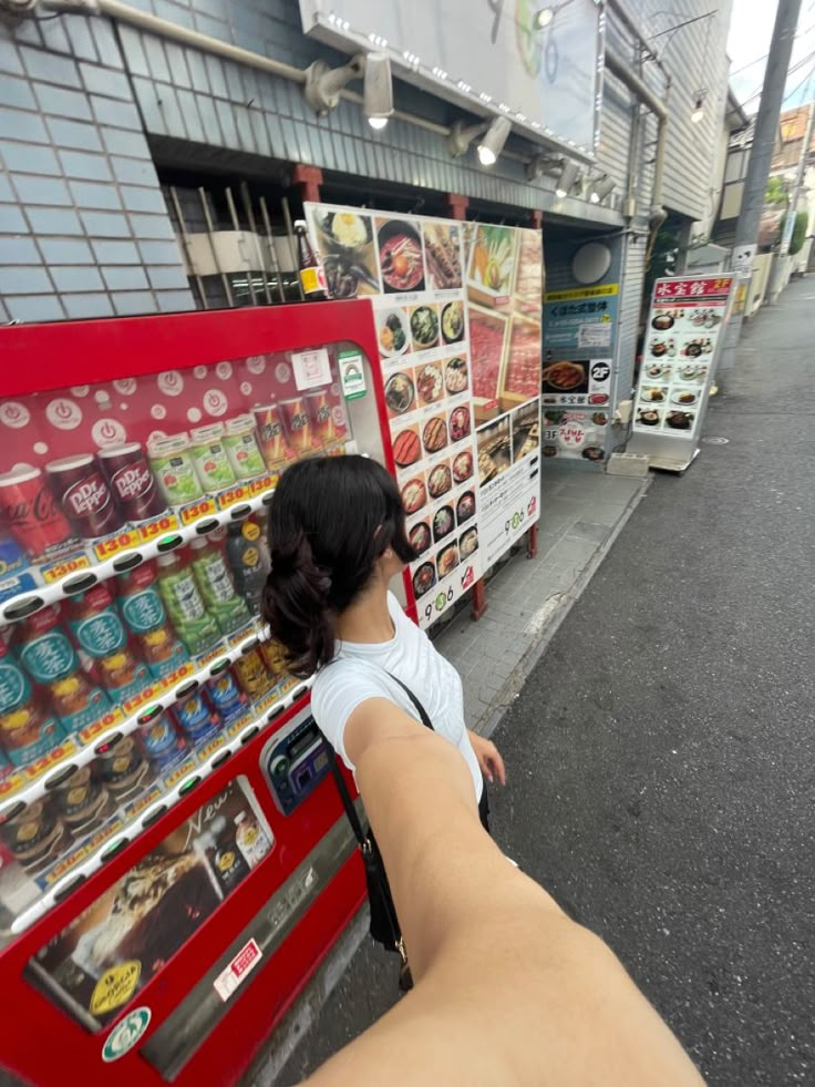 a woman is pointing her finger at a vending machine