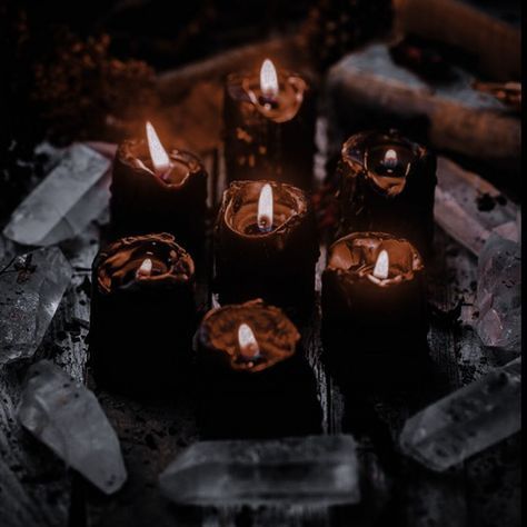 many lit candles sitting on top of a table next to crystal blocks and crystals in the background