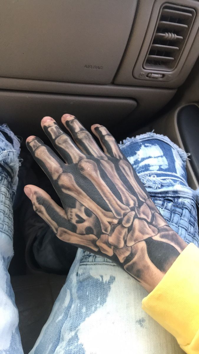 a person's hand with a skeleton tattoo on it sitting in the back seat of a car