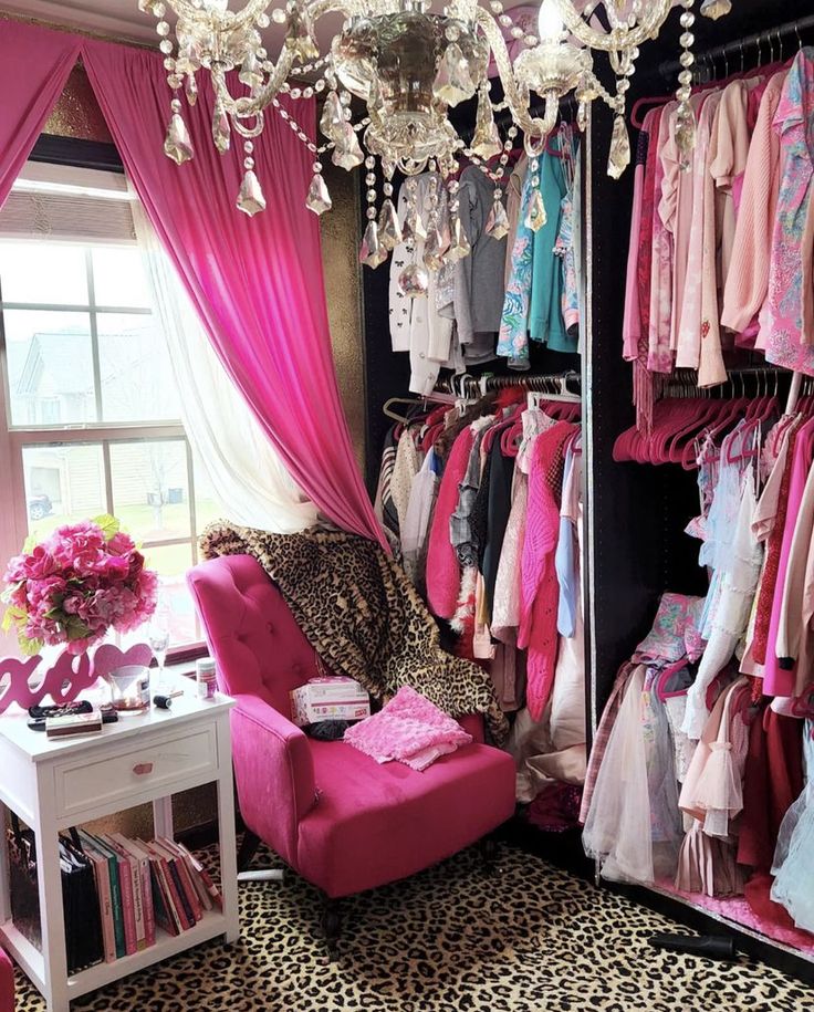 a pink chair sitting in front of a closet filled with clothes