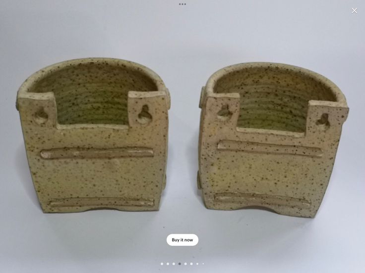 two ceramic pots sitting side by side on a white surface