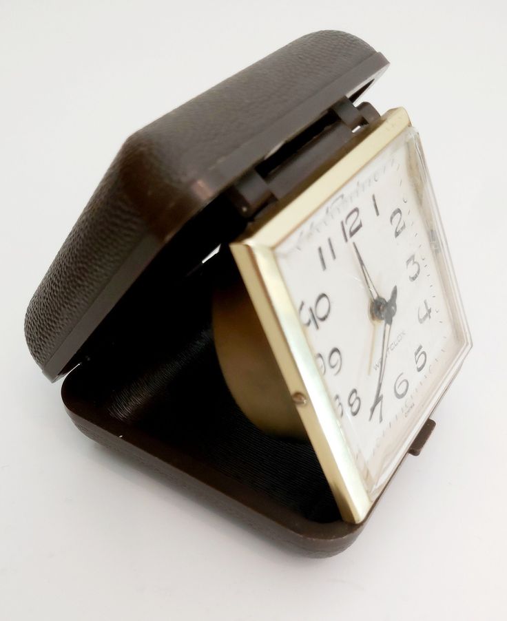 an alarm clock sitting on top of a black stand with a brown leather strap around it