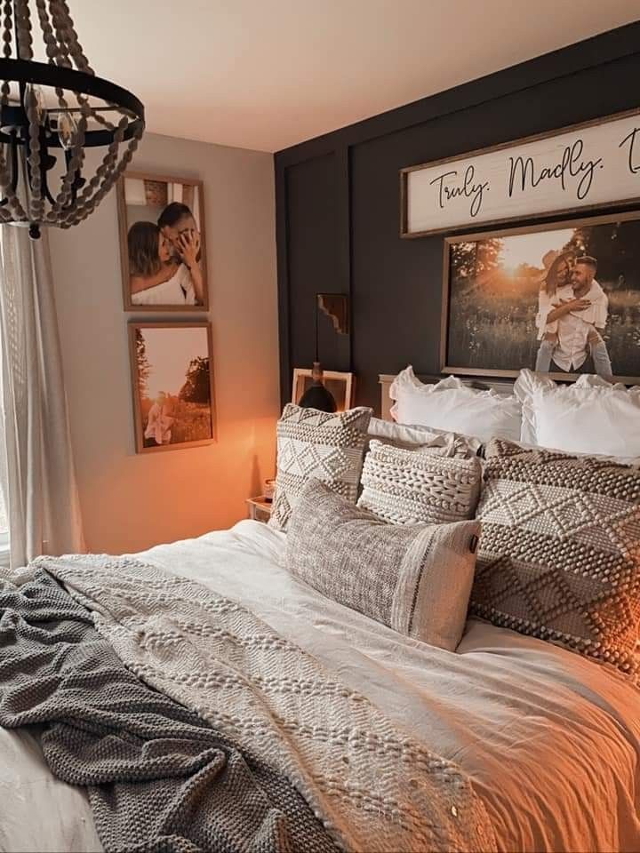 a large bed sitting in a bedroom next to a window with pictures on the wall