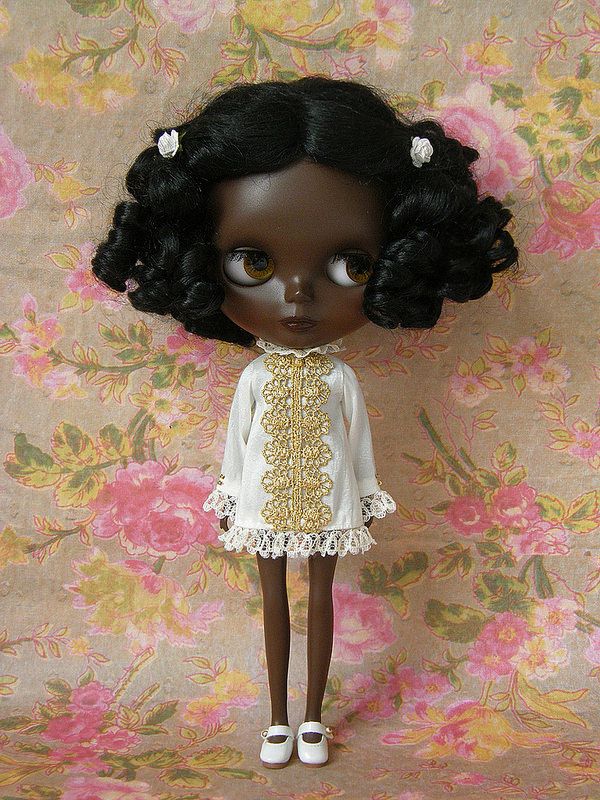 a doll with black hair wearing a white dress